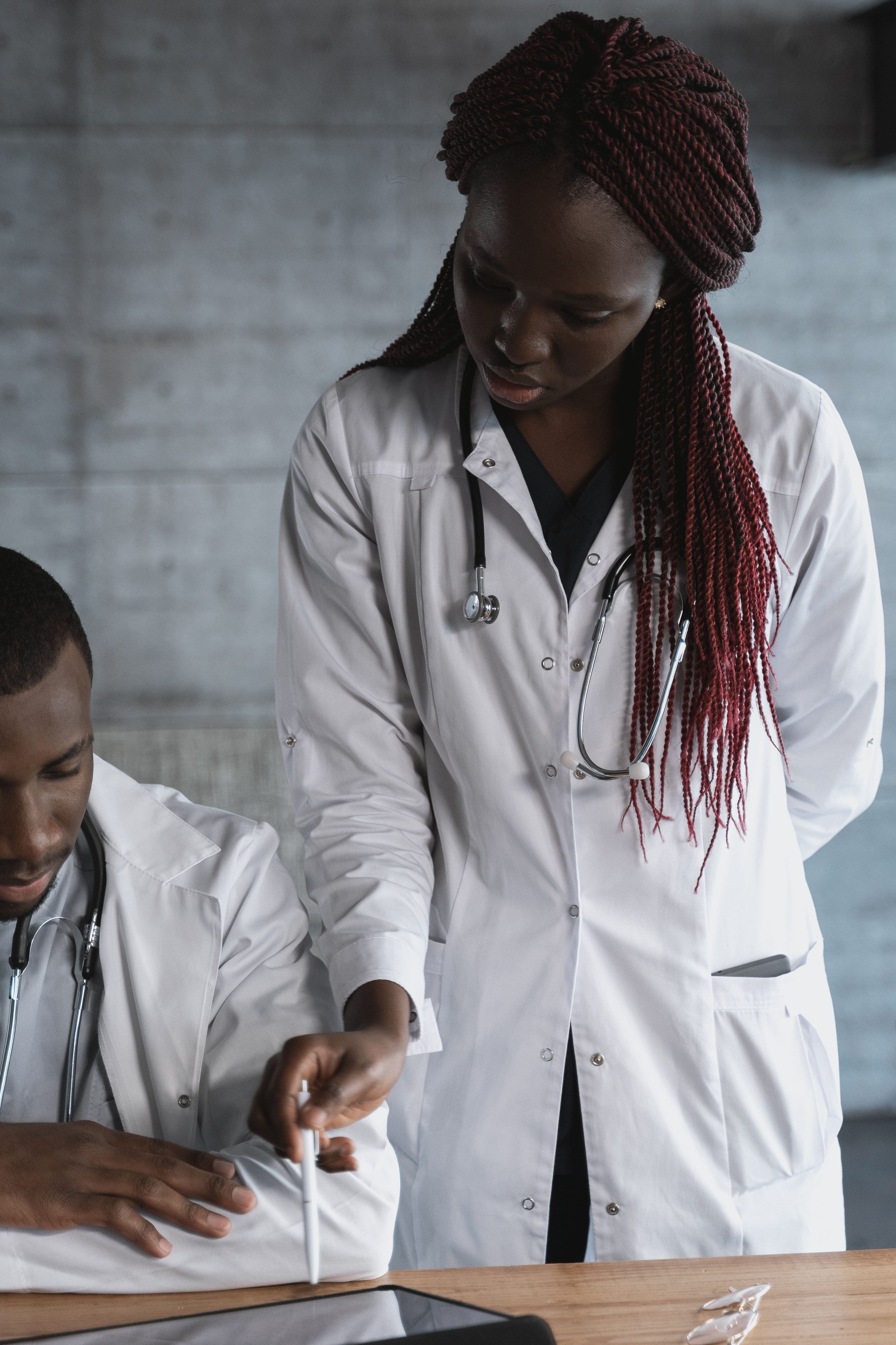 Two African healthcare professionals reviewing notes together in a clinical setting. Demonstration photography, not a photograph of Beulah Group Hospital, its staff, or its facilities.