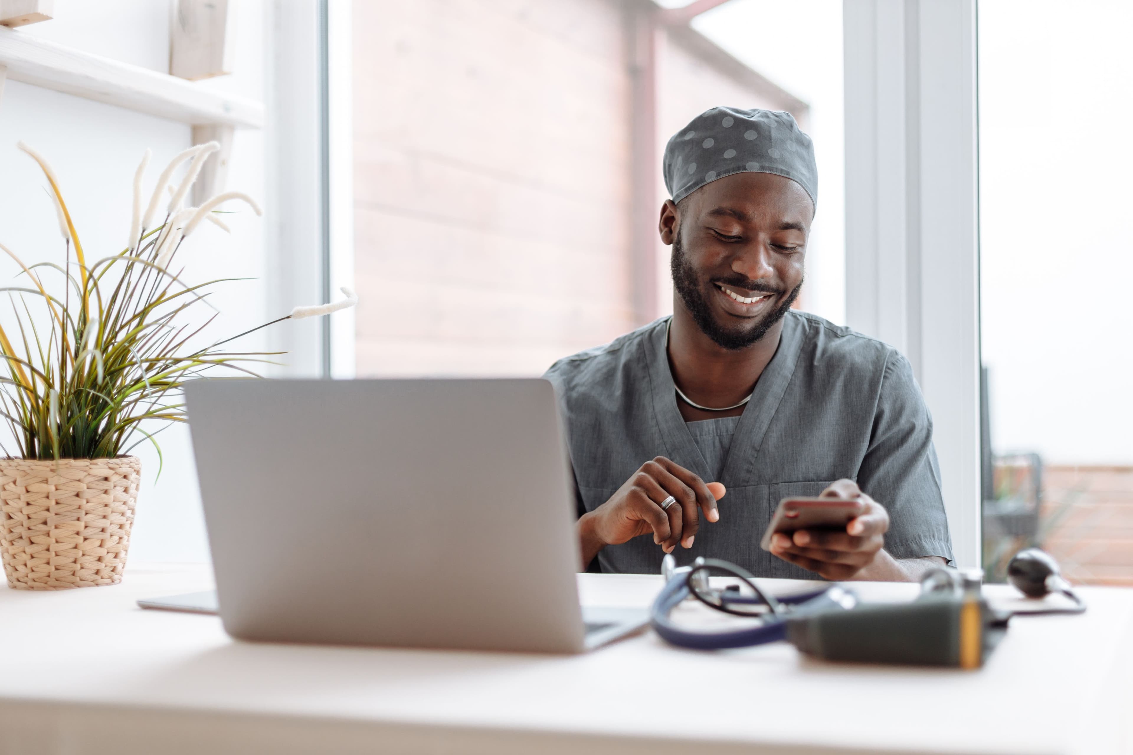 A healthcare professional smiling while speaking with someone by phone at a bright desk. Demonstration photography, not a photograph of Beulah Group Hospital, its staff, or its facilities.