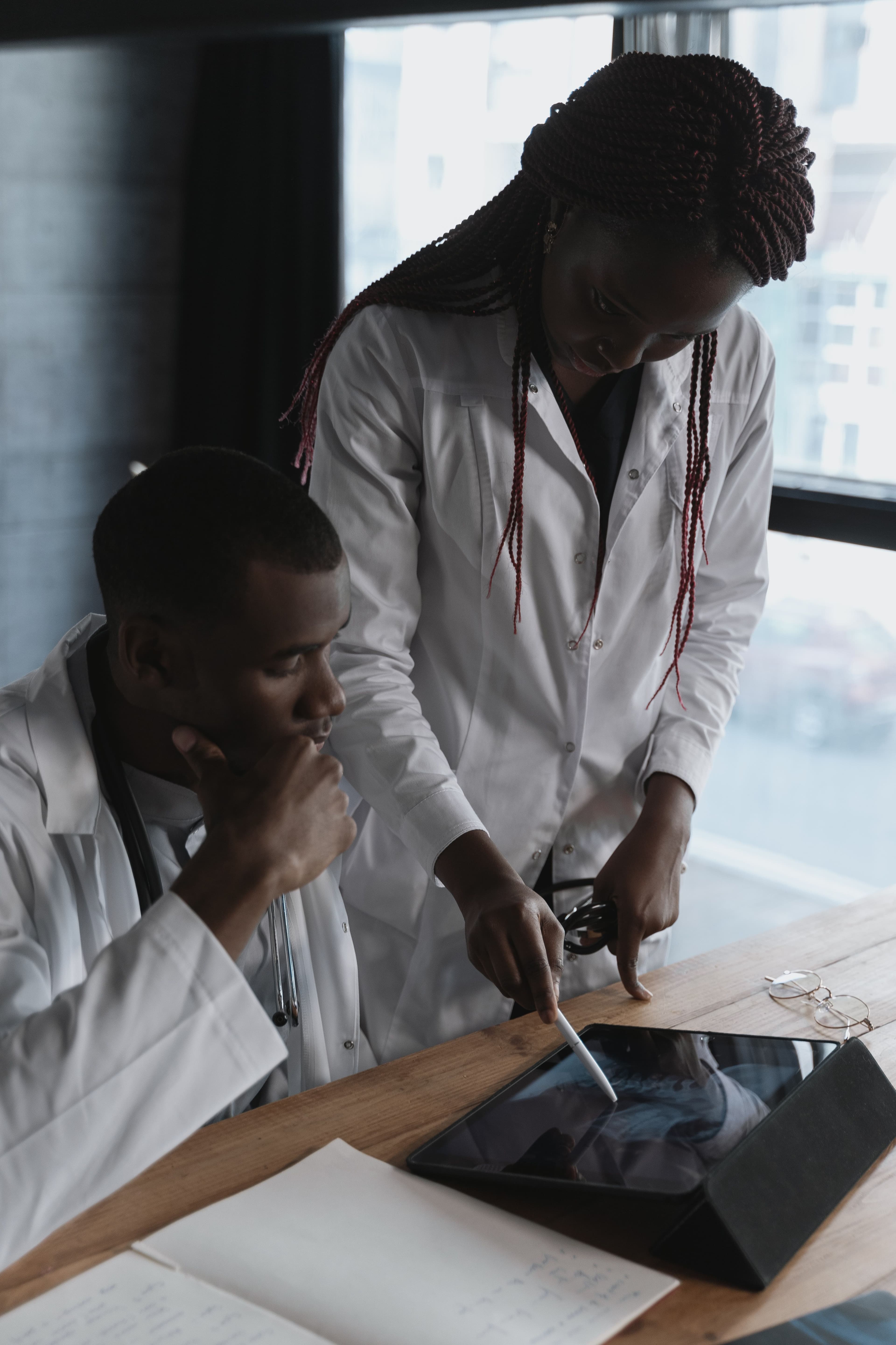 African healthcare professionals reviewing clinical information together on a tablet. Demonstration photography, not a photograph of Beulah Group Hospital, its staff, or its facilities.
